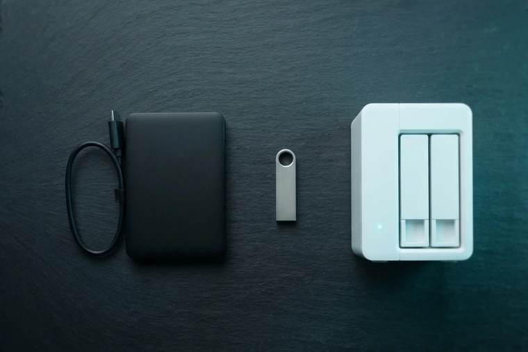 Ilustración de la regla 3-2-1: disco externo, memoria USB y NAS sobre una mesa de pizarra